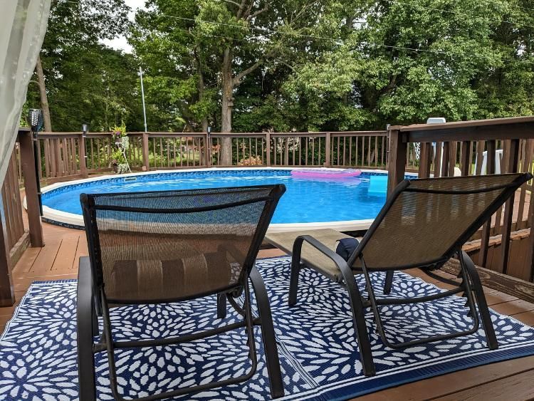 Two rocking chairs are sitting on a rug next to a swimming pool.