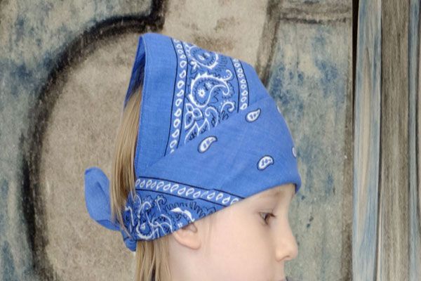 A little girl wearing a blue bandana on her head