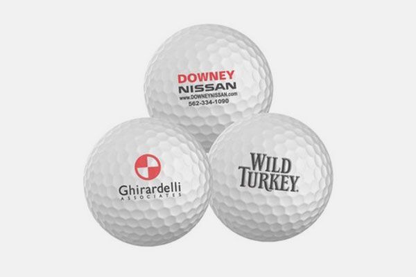 Three golf balls with different logos on them are stacked on top of each other.