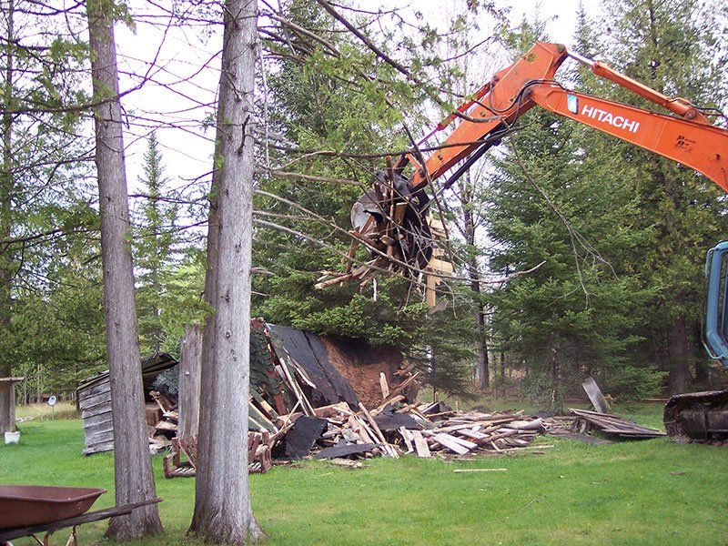 small cabin getting demolished by orange equipment