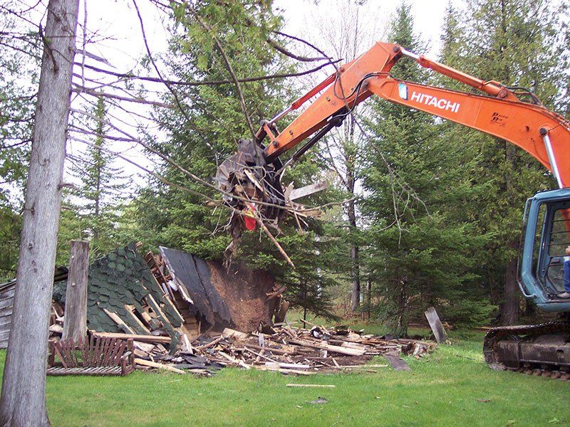 small cabin getting demolished by heavy-duty equipment