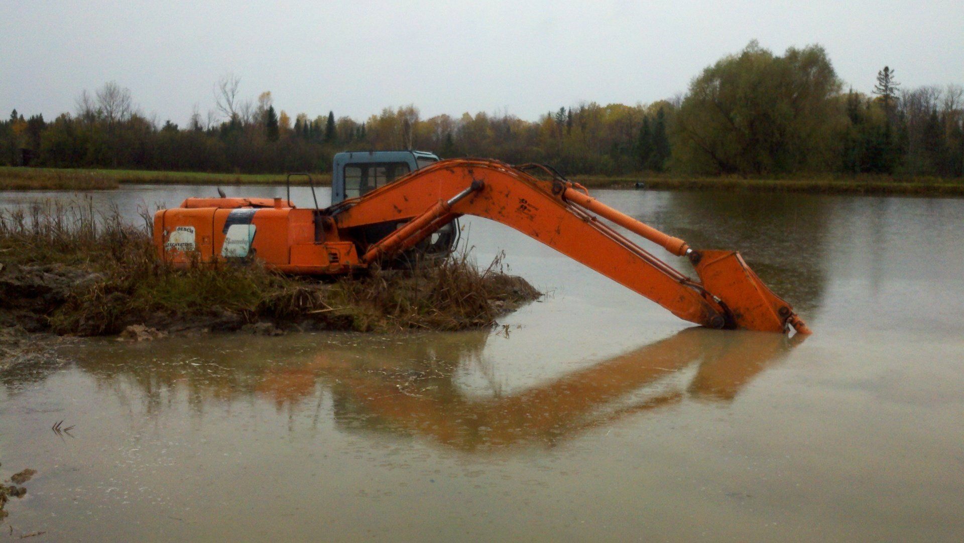 orange heavy-duty equipment by the pond