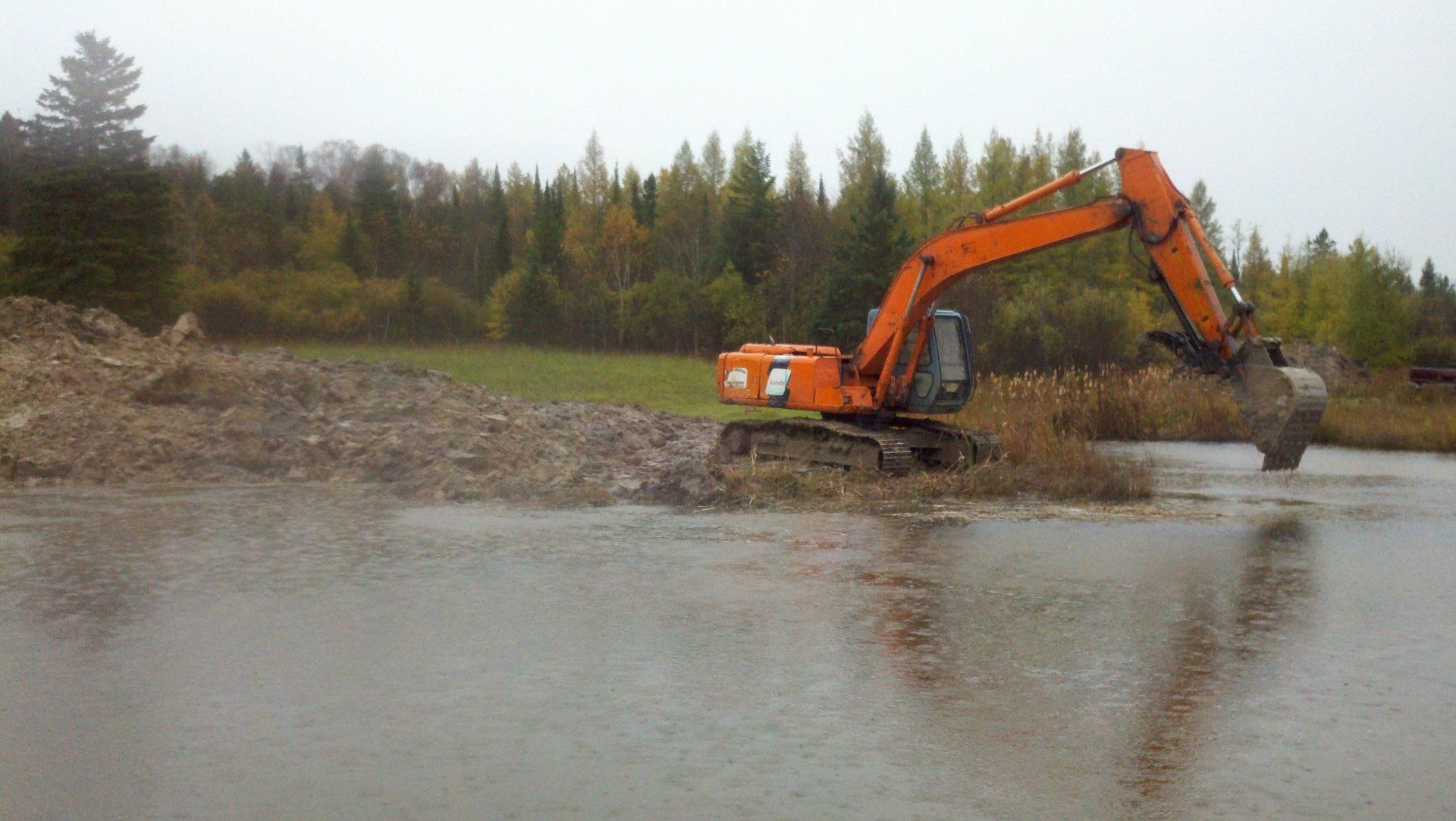 orange heavy-duty equipment near the pond