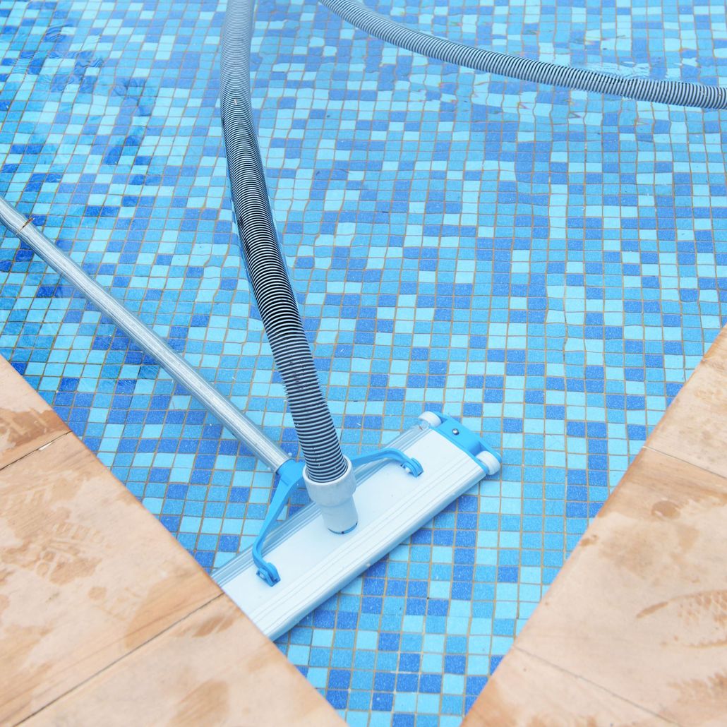 Pool vacuum cleaner in a swimming pool cleaning the blue tiled bottom.