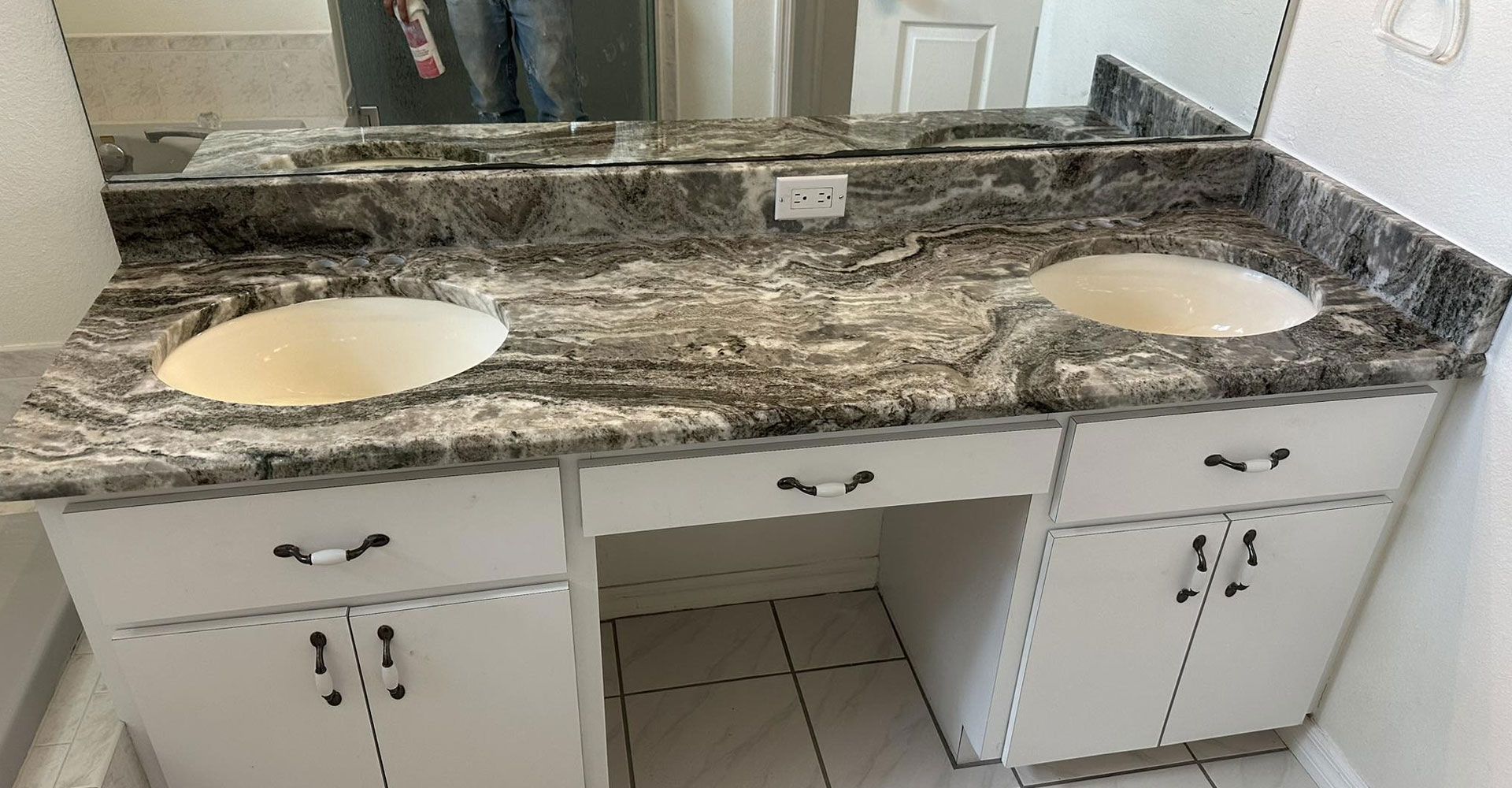 Double bathroom vanity with gray and white countertop, two sinks, and white cabinets.