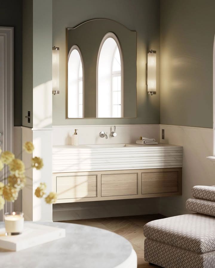 Bathroom with arched mirror, white and wood vanity, light green walls, and decorative accents.