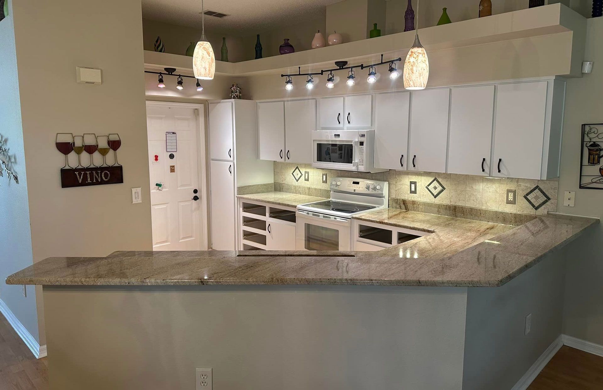 Kitchen with white cabinets, granite countertops, and decorative lighting.