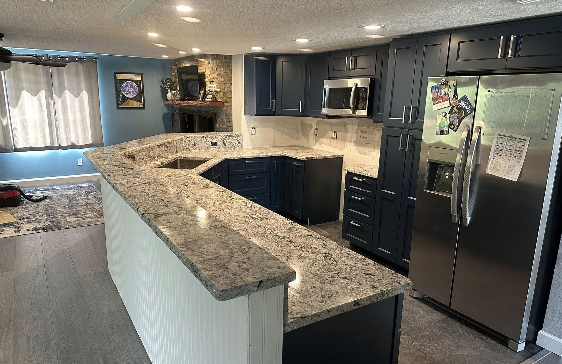 Kitchen with navy cabinets, granite countertops, and stainless steel refrigerator.