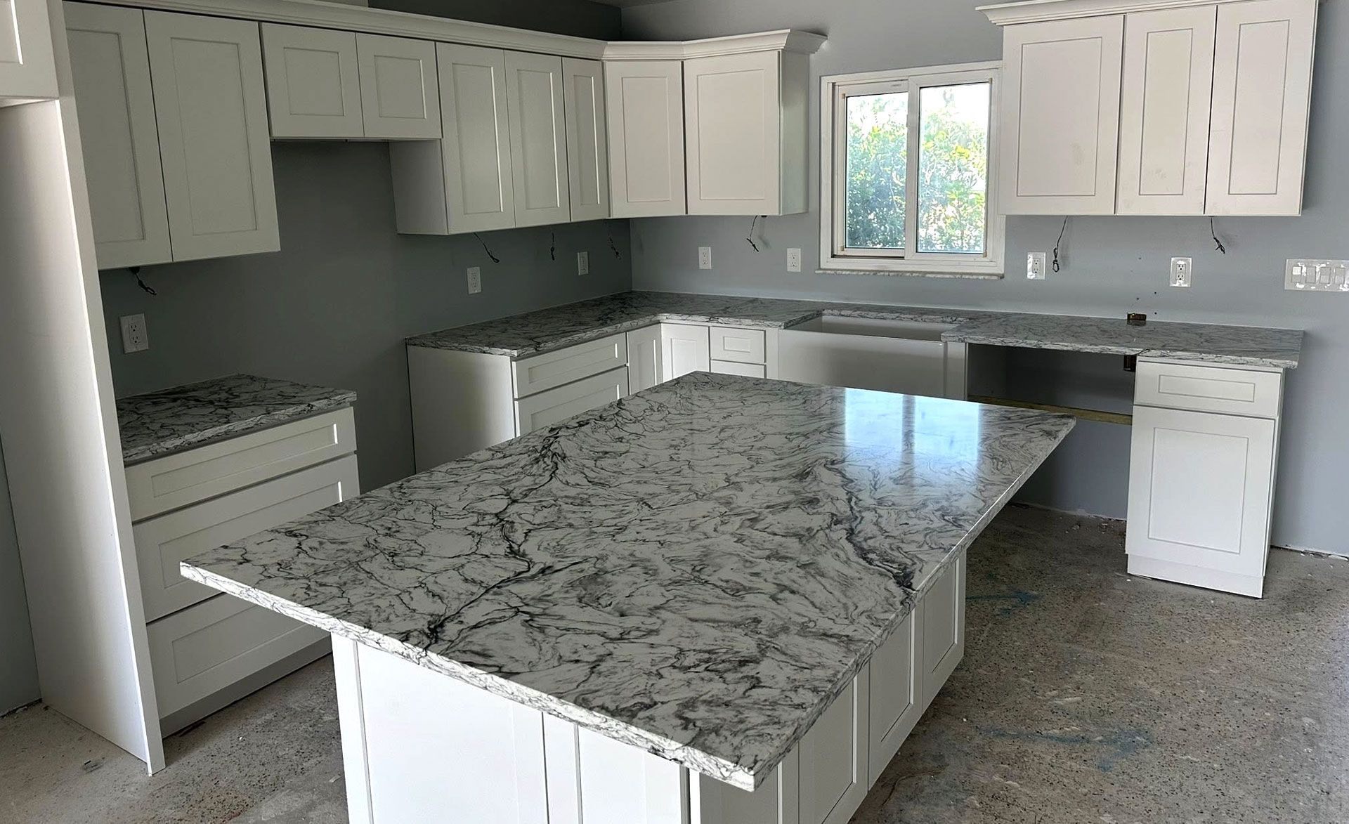 White kitchen with gray countertops and a large island.