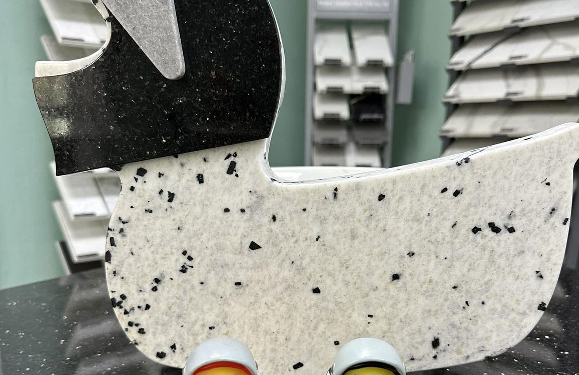 Duck-shaped display, speckled white, with black head and two ceramic feet, in front of a countertop display.