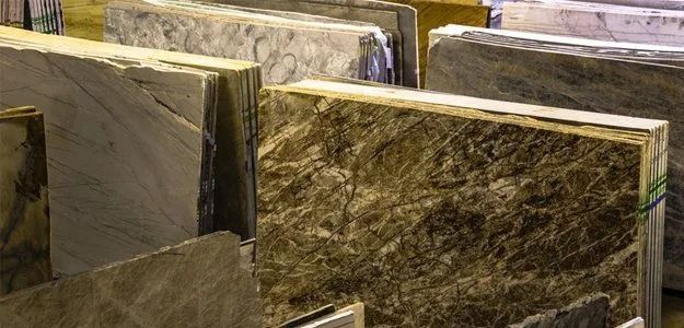 Slabs of various stone materials, possibly granite or marble, in a showroom or warehouse.