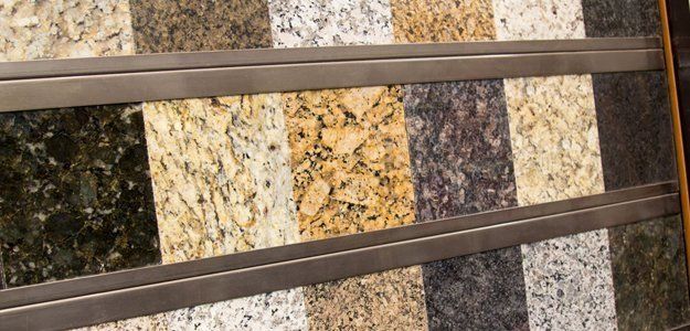 Granite countertop samples in various colors, displayed with metal trim.