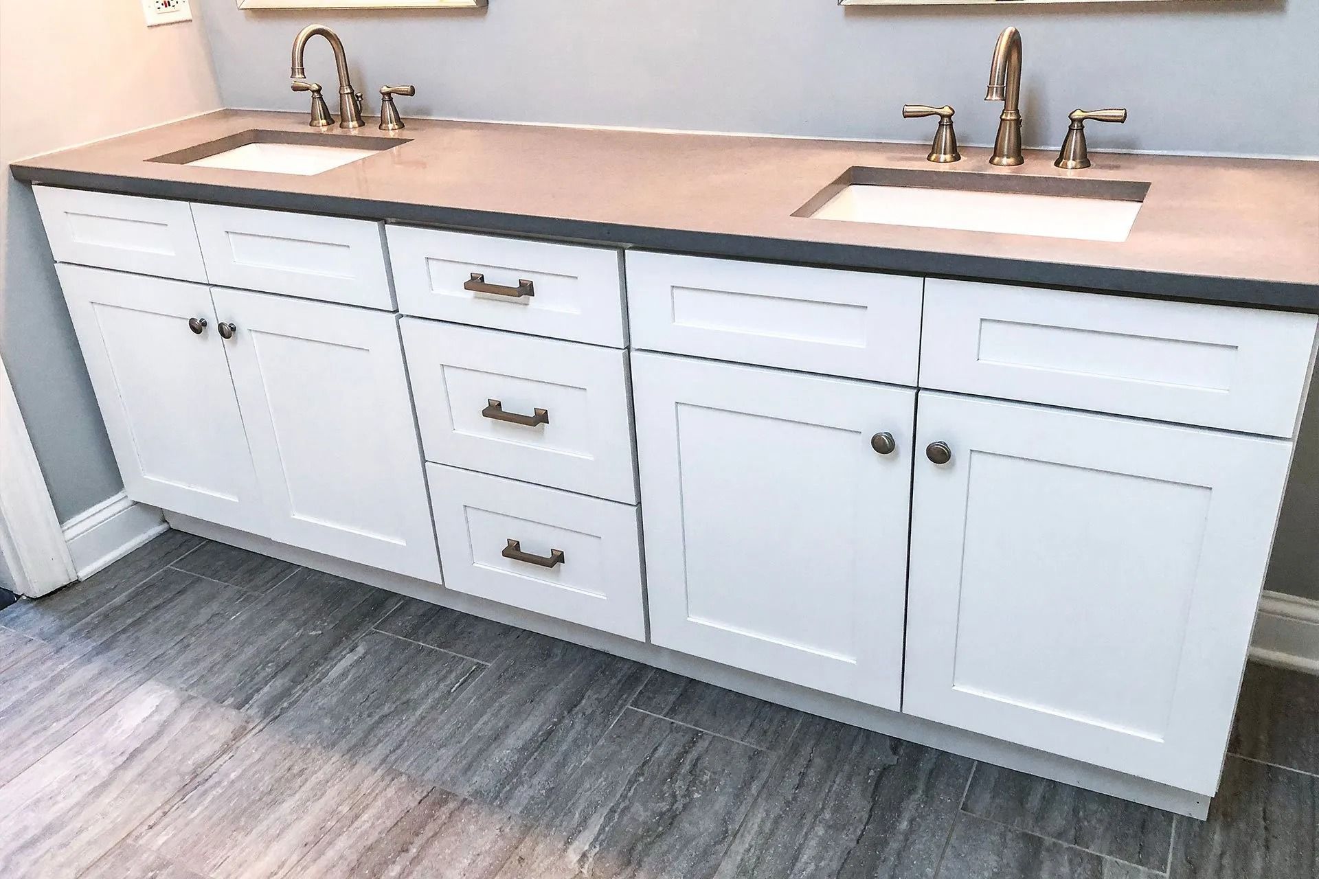 White double sink vanity with gray countertop and silver faucets in a bathroom.