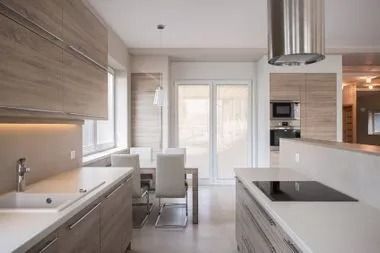 Modern kitchen with light wood cabinets, white countertops, and a dining table by the window.
