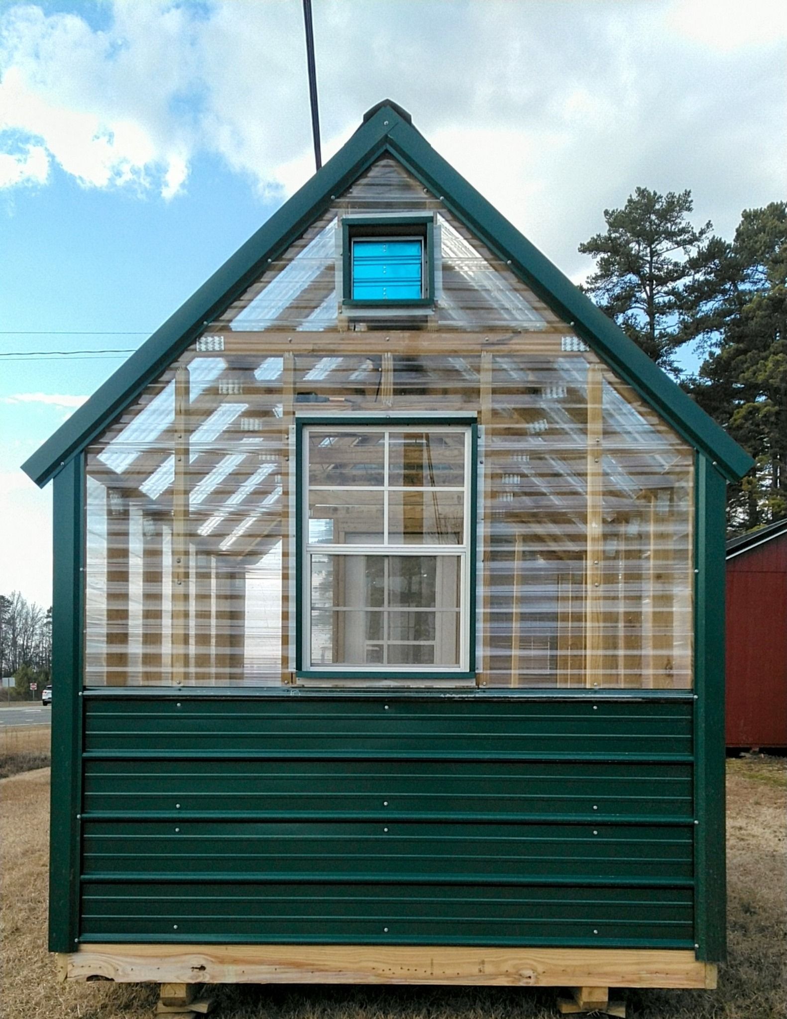 A greenhouse with a window and a blue sky in the background