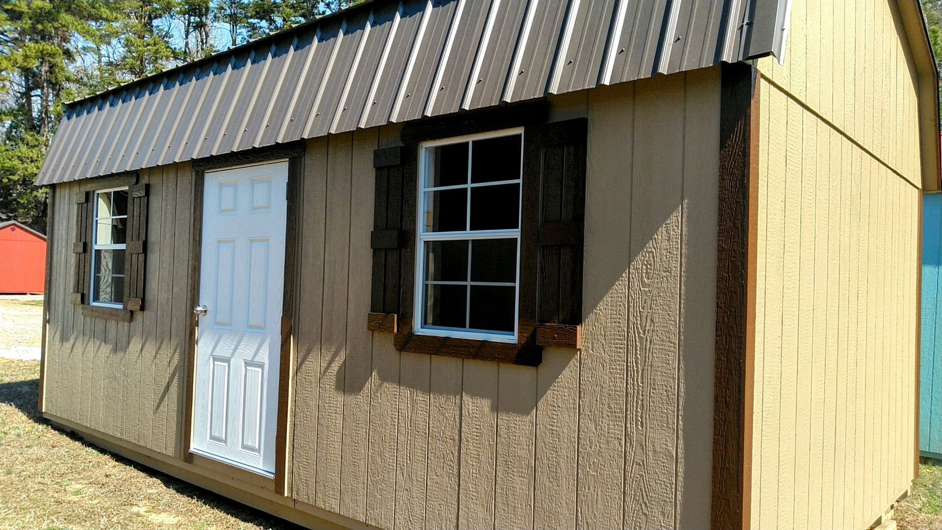 A small wooden shed with a window and shutters.