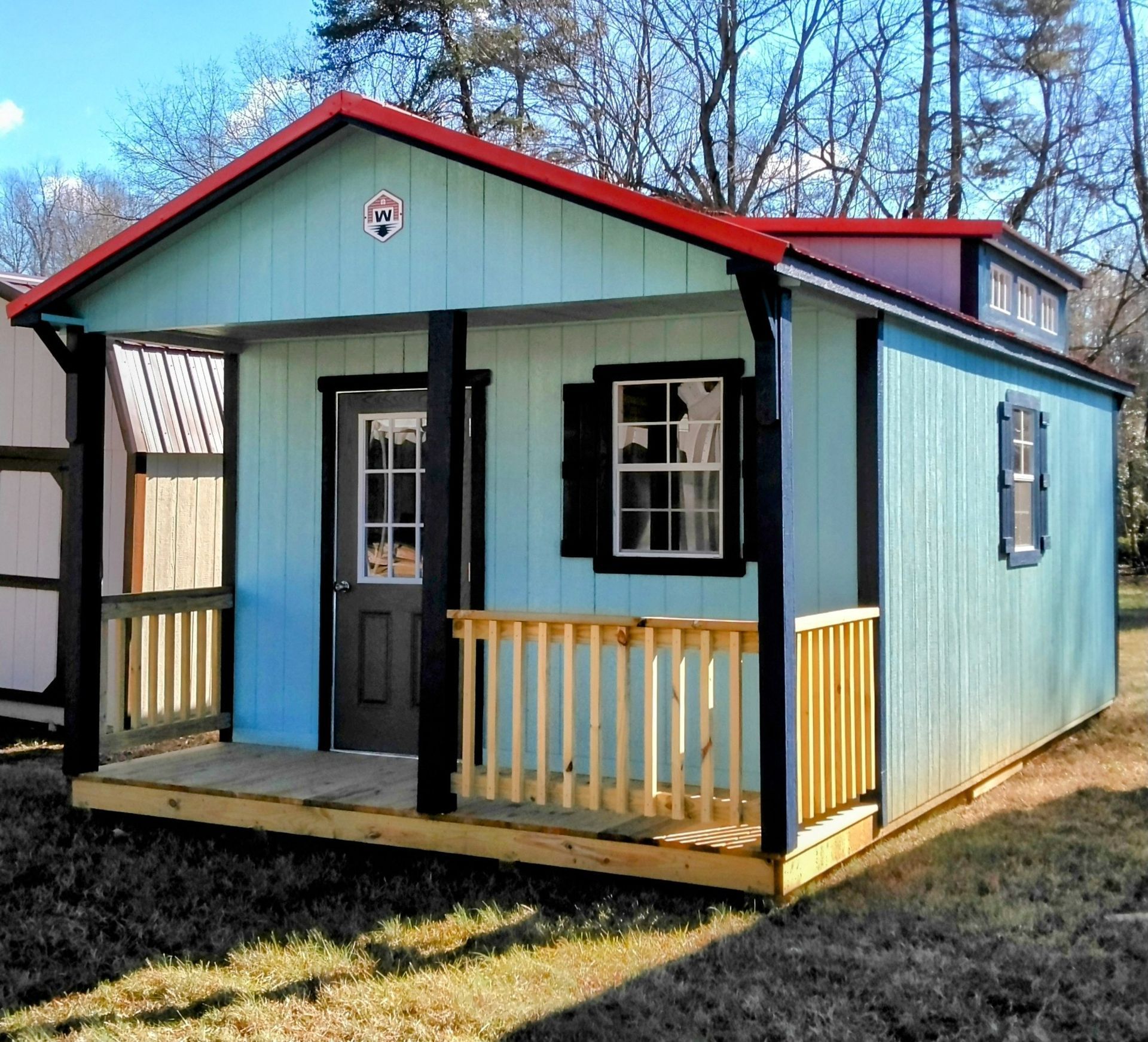 A small blue house with a red roof and a porch