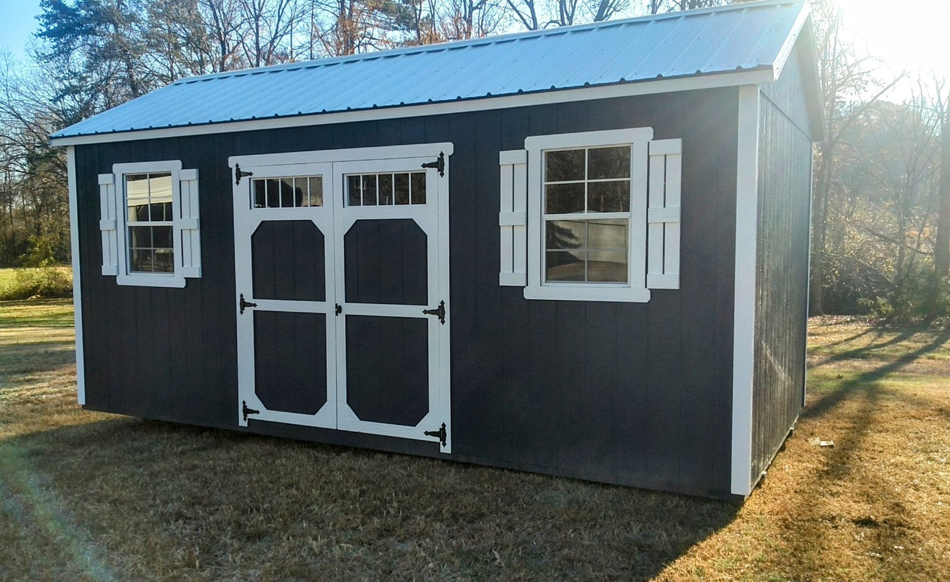 A black shed with white windows and shutters