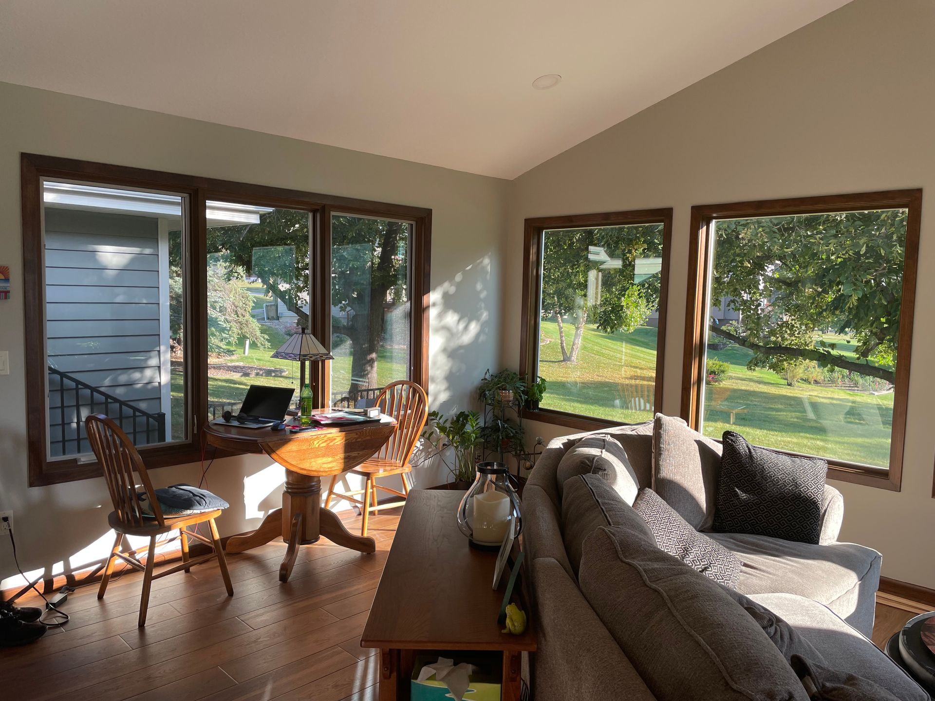 Sunlit living room with windows, table, sofa, and chairs.