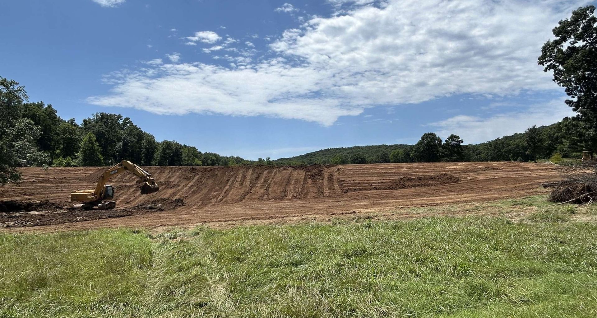 A large dirt field with a bulldozer in the middle of it.