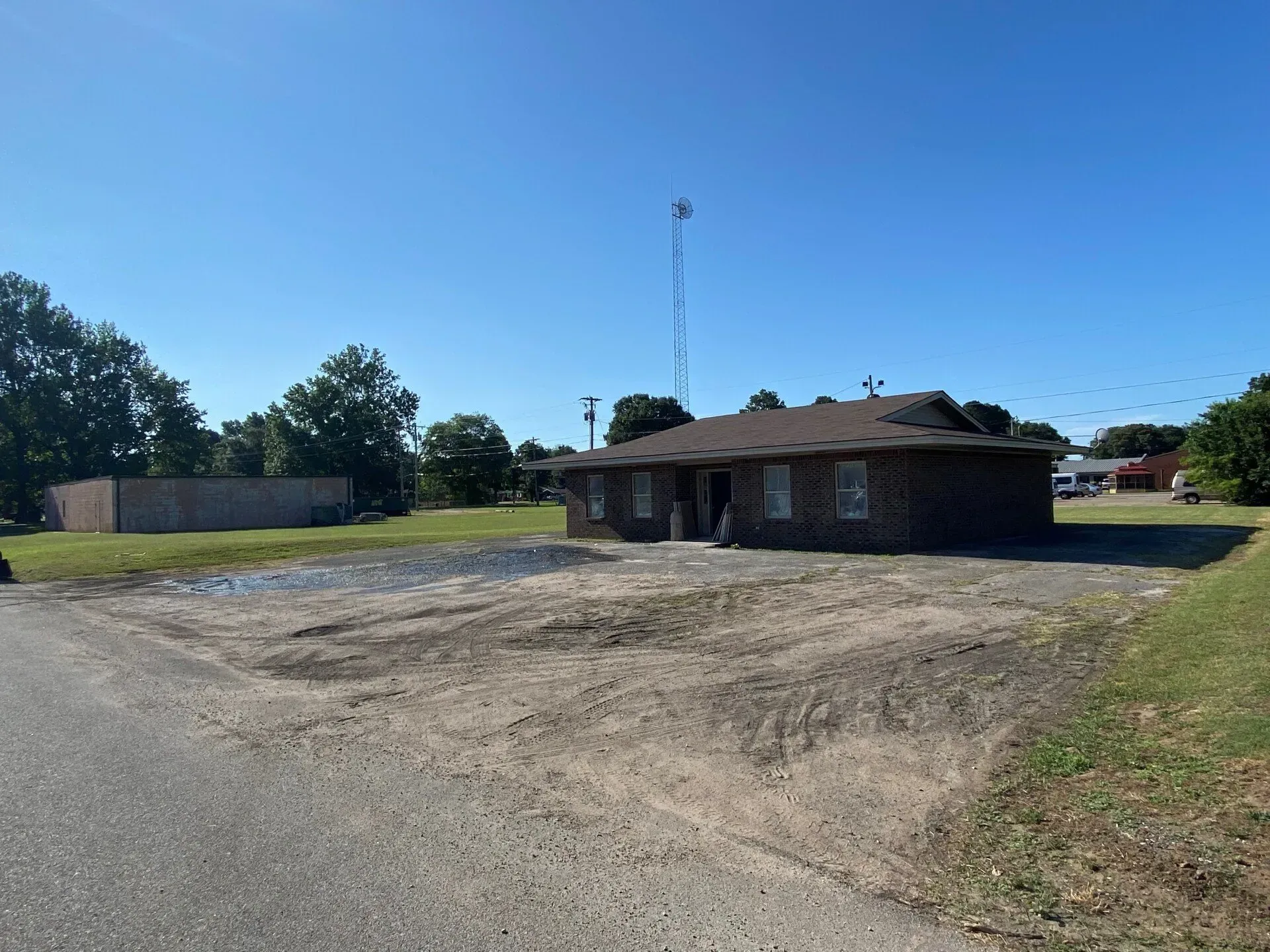 Low brick building beside a gravel lot under a clear blue sky