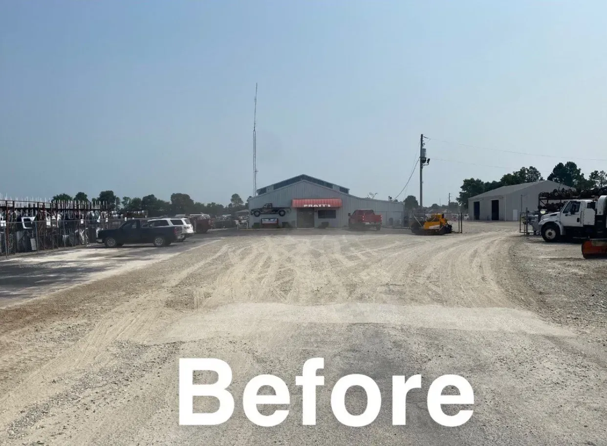 Before view of a gravel lot with heavy equipment and a building in the distance