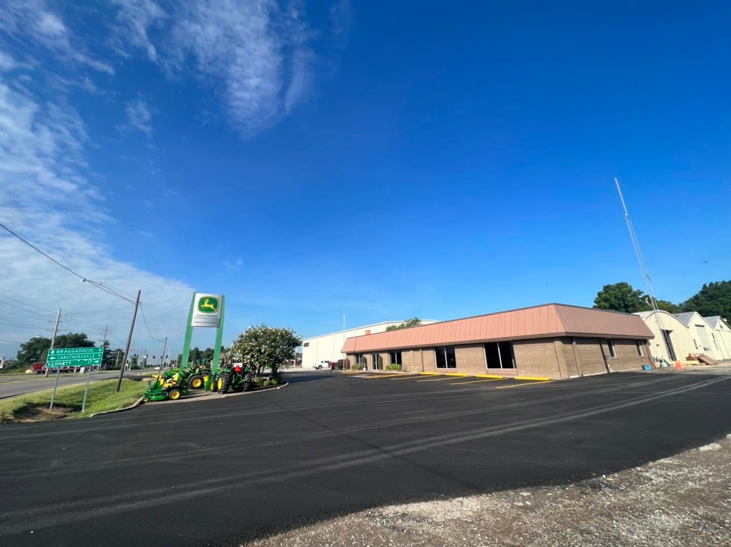Wide street corner with a gas station sign, low beige building, and bright blue sky