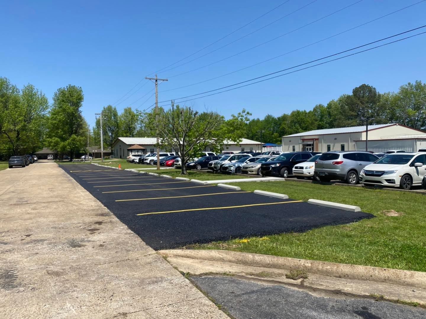 Parking lot with cars beside low buildings on a sunny day