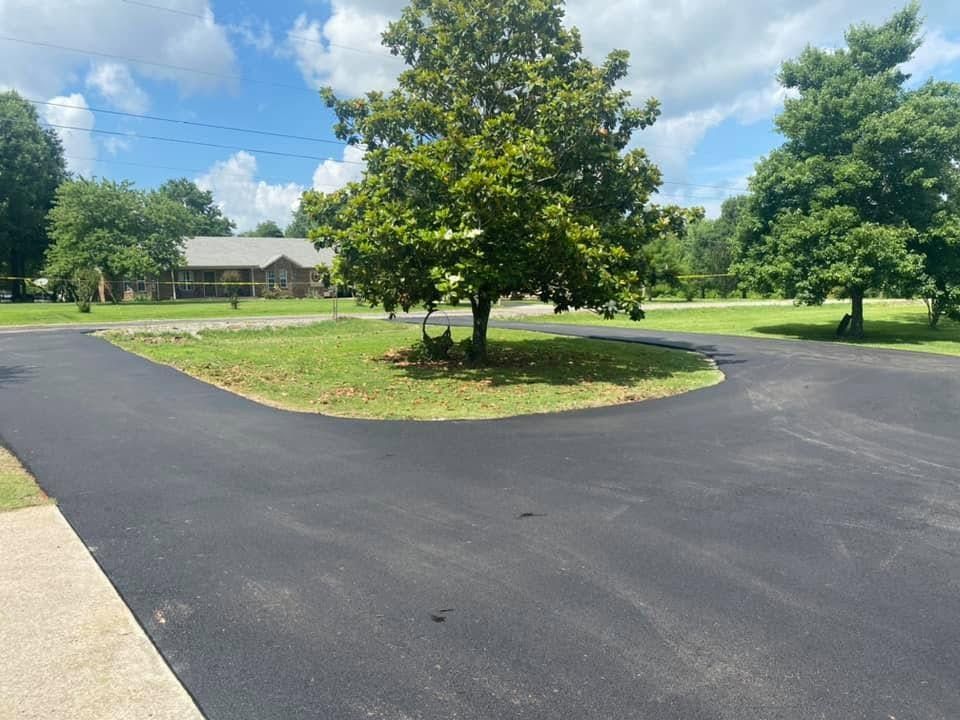 Paved parking loop around a tree island in a green park under a partly cloudy sky