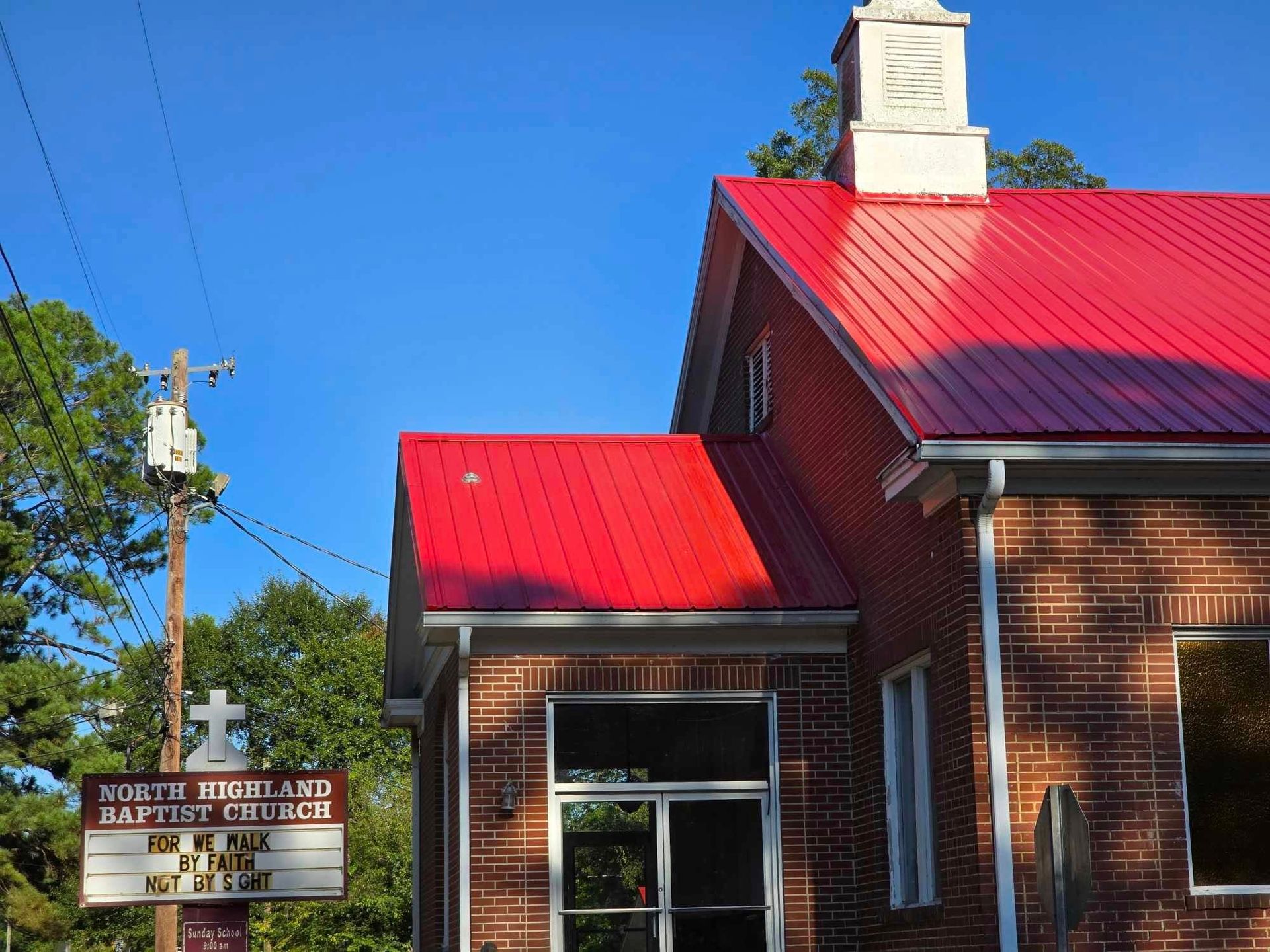 North Highland Baptist Church with a red metal roof and sign.