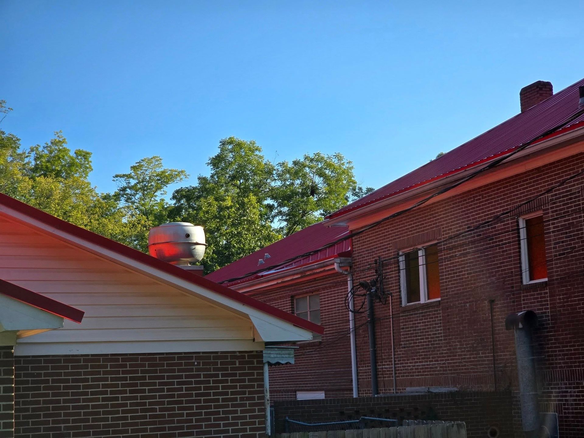 Buildings with red roofs, brick and siding exterior, blue sky, trees in the background.