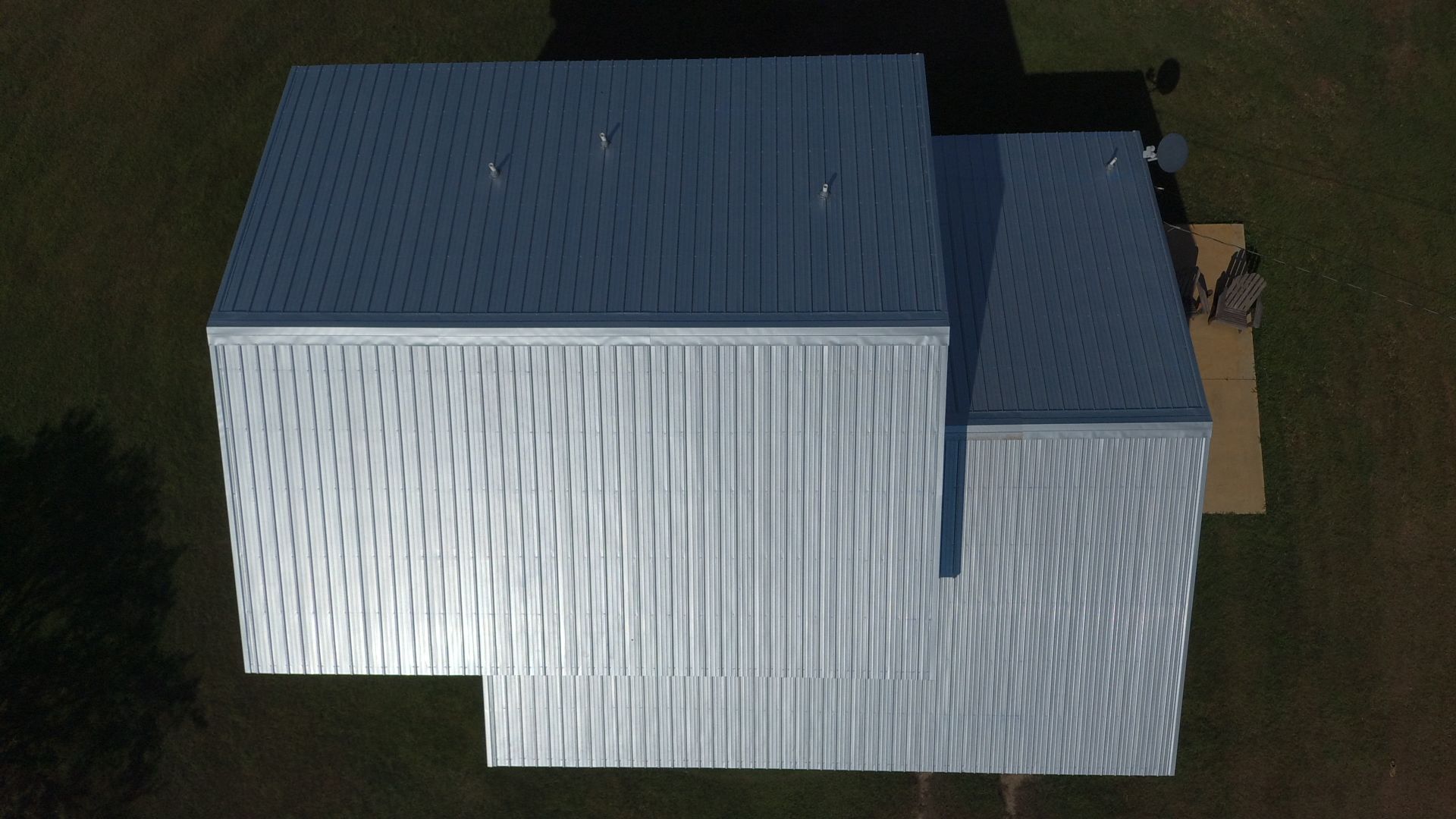 Overhead view of a modern metal building with a light-colored roof and siding on a green lawn.