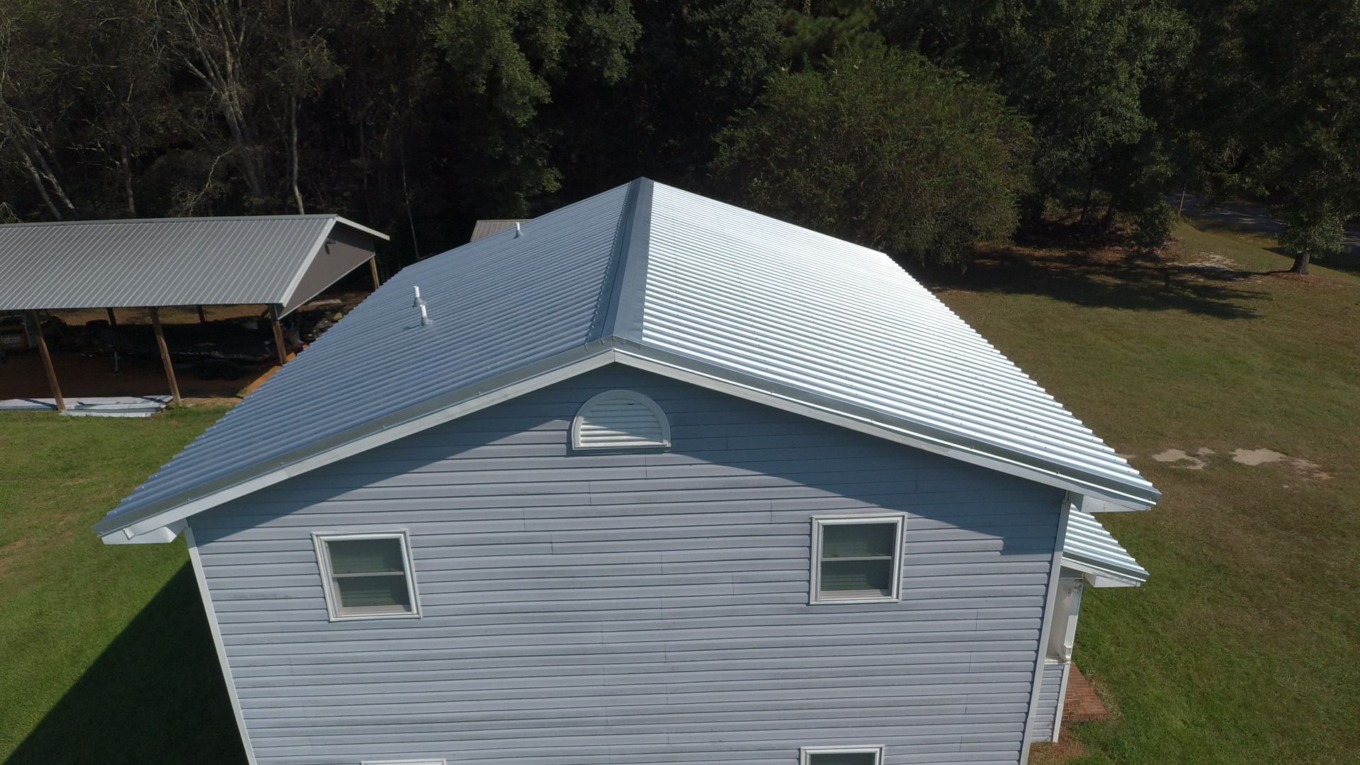 House with light blue siding, white trim, and a corrugated silver metal roof.
