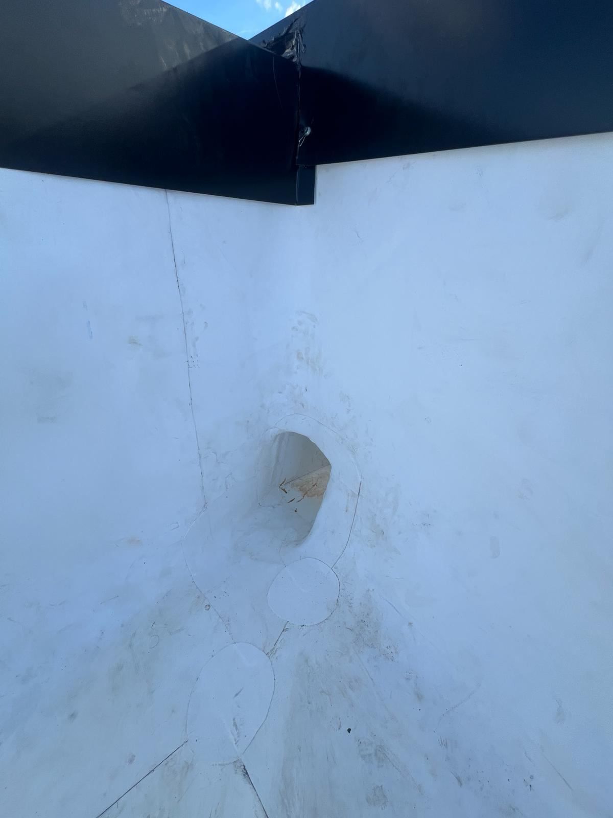 Interior of a white, funnel-shaped structure with a hole at its bottom. The top is black.