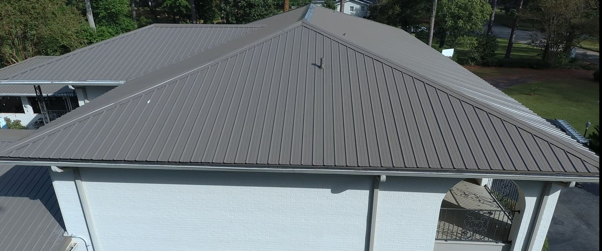 Gray metal roof of a house with a white exterior.