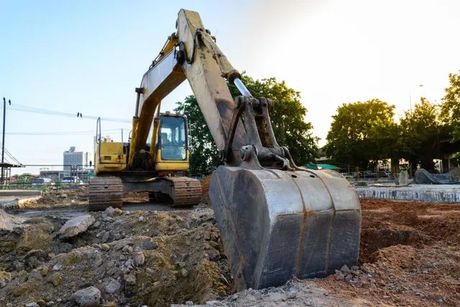 a yellow excavator is digging a hole in the ground at a construction site