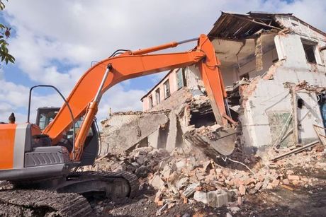 a large orange excavator is demolishing a building 