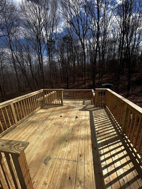 Wooden deck with railings overlooking leafless trees under a partly cloudy sky