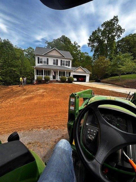 View from a tractor at a house with a fresh red dirt driveway under construction
