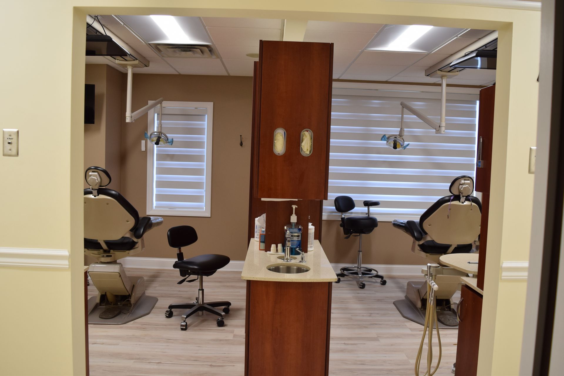 A dental office with three dental chairs and a sink.