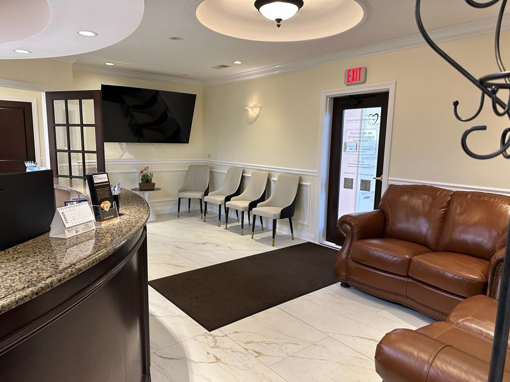 A waiting room with a couch and chairs in a dental office.