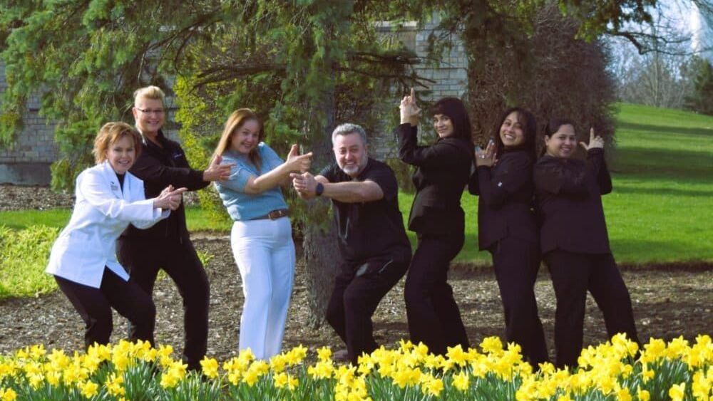 A group of people are posing for a picture in front of a field of yellow flowers.