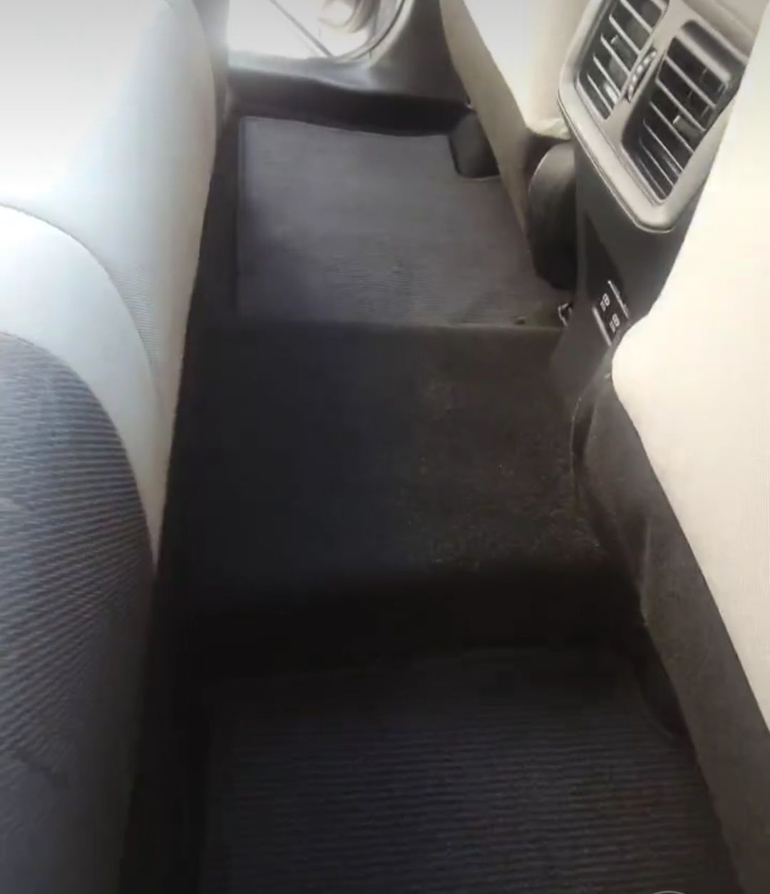 the back seat of a car with a black carpet and white seats