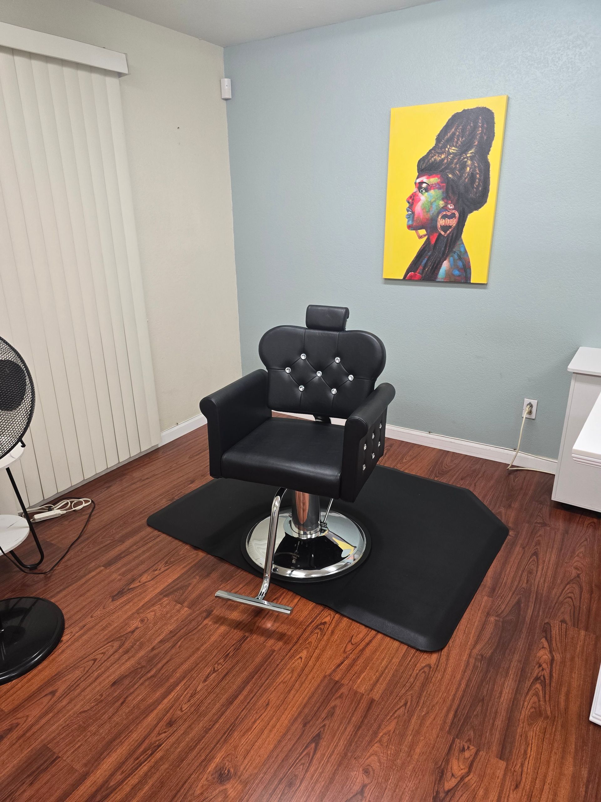 A barber chair is in a room with a painting on the wall above it