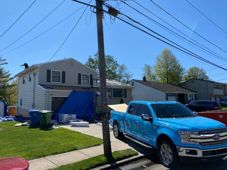 A blue truck is parked in front of a house under construction