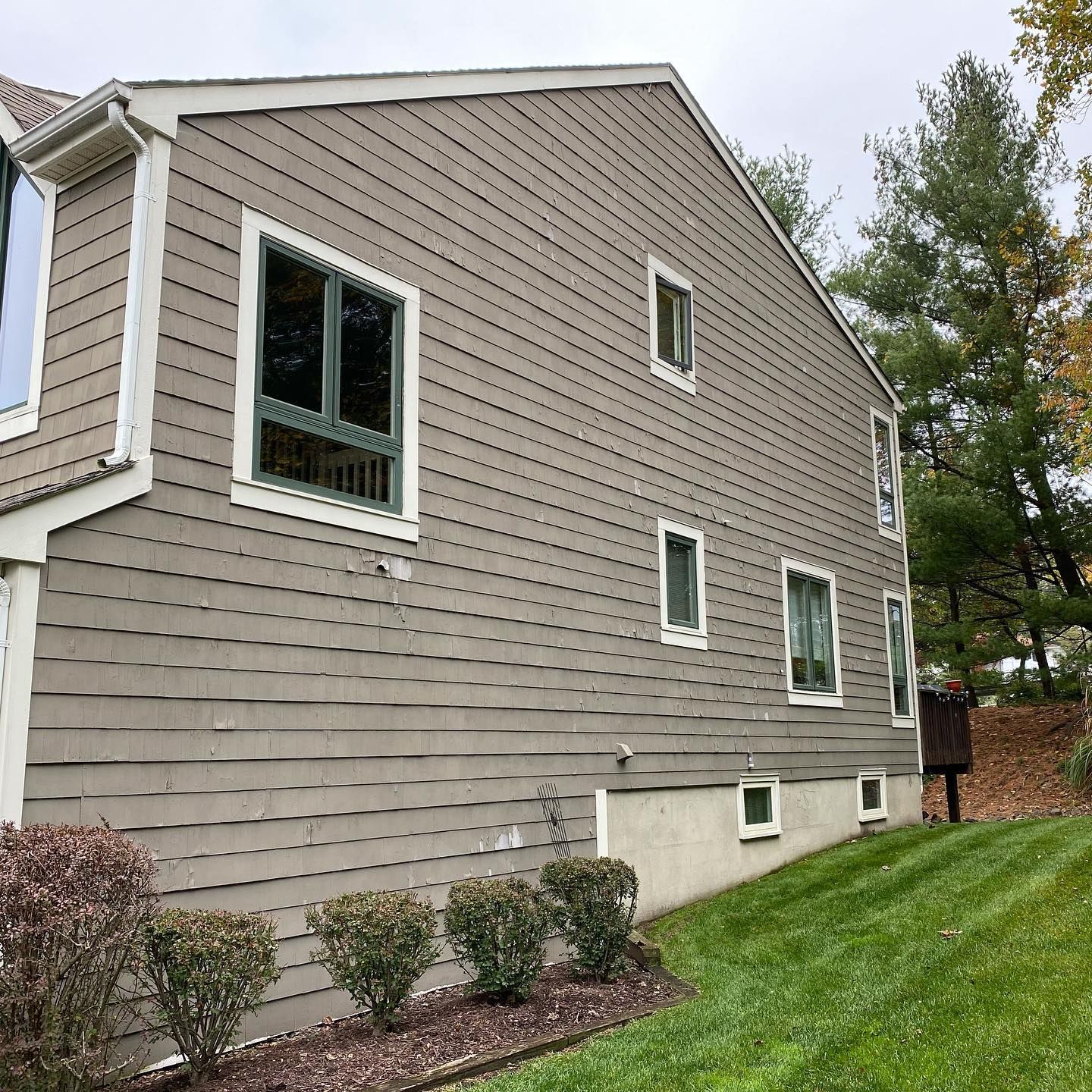 A large house with a lot of windows is sitting on top of a lush green hillside
