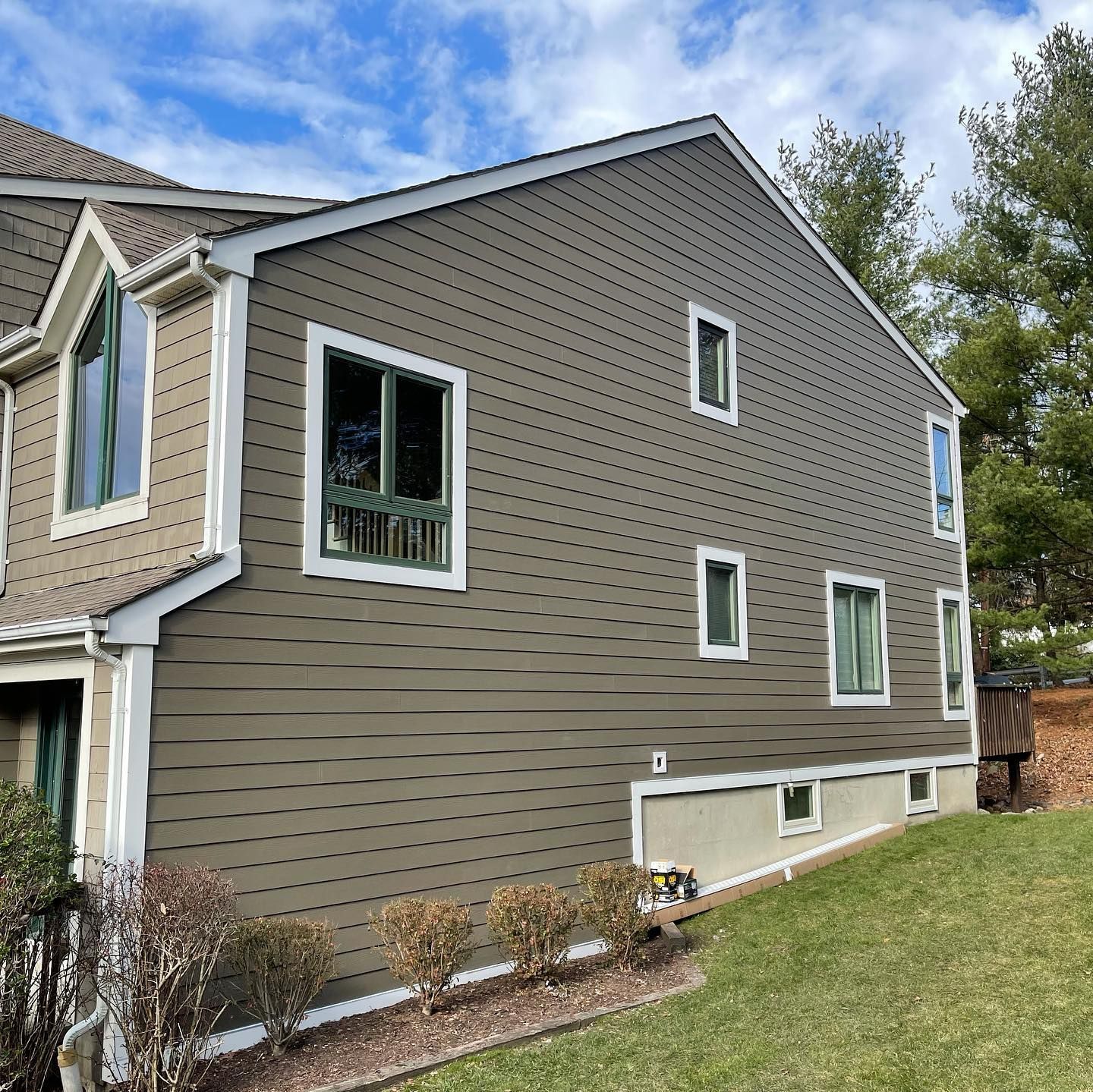 A large house with a lot of windows is sitting on top of a lush green hillside