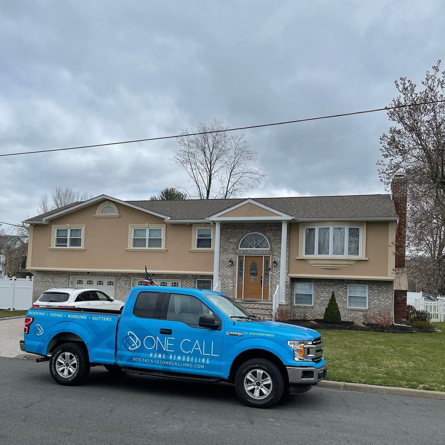 A blue one call truck is parked in front of a house