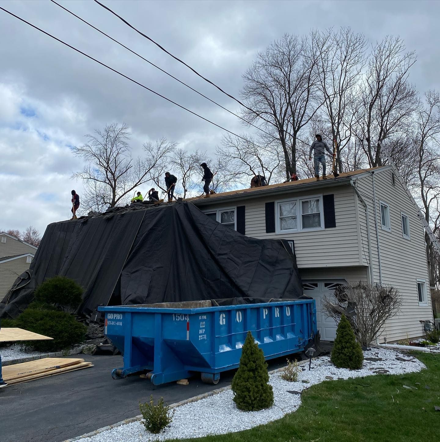 A house is being remodeled with a blue dumpster in front of it