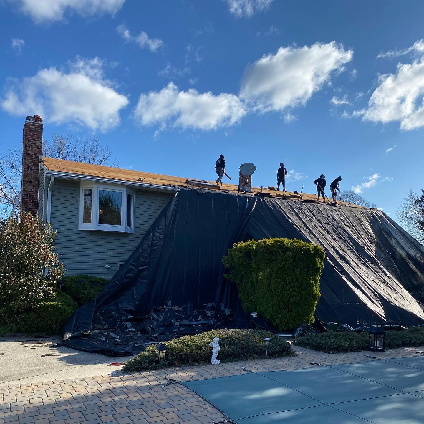 A group of people are working on the roof of a house